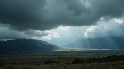 An expansive landscape view with rolling dark storm clouds covering the sky, casting shadows over fields and mountains