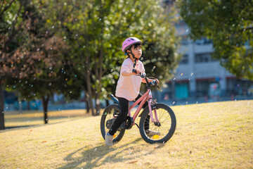 Fototapeta premium 公園で自転車に乗って遊ぶ女の子