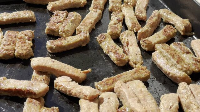 cevapcici on the grill are grilled and turned