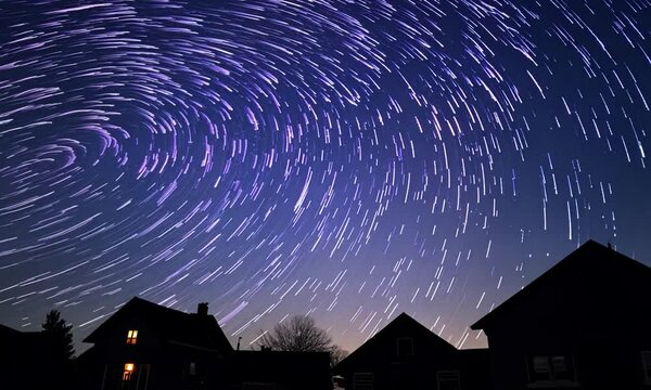 Timelapse of moving stars in night sky above the houses. 4K
