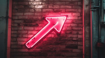 Neon arrow sign on brick wall at night