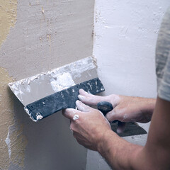 A man plastering a wall with a spatula
