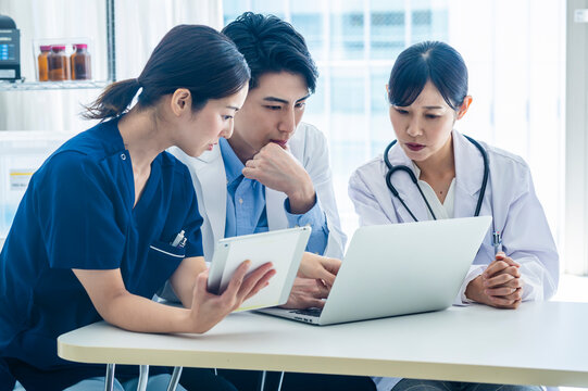 Multidisciplinary Medical Team Planning Treatment in Office
Three healthcare workers in a medical office setting are engaged in a friendly discussion around a laptop, preparing a treatment