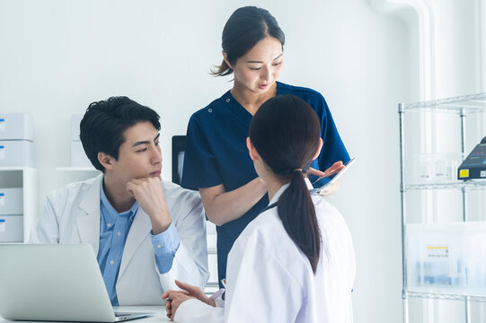 Multidisciplinary Medical Team Planning Treatment in Office
Three healthcare workers in a medical office setting are engaged in a friendly discussion around a laptop, preparing a treatment