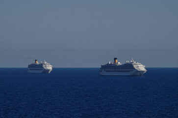 Obraz premium Mega family cruiseship cruise ship liners Favolosa and Fortuna anchored offshore of Civitavecchia Rome, Italy before reactived after Covid pandemic with other vessels in port and coastline