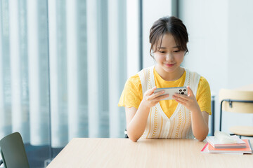 Fototapeta na wymiar カフェでスマホを見る学生【撮影協力:スカパー東京メディアセンター】