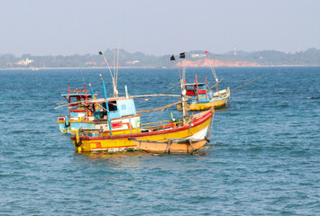 Fototapeta premium A yellow boat is floating in the ocean next to a blue boat