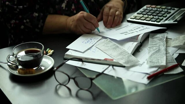 Hands calculating expenses with pen and calculator on table	