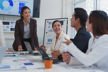 Asian businesspeople are working together in a modern office, collaborating on a project and having a productive meeting, using a laptop and analyzing charts and graphs displayed on a screen