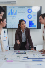 Business team analyzing financial data and discussing marketing strategy in a meeting room, using...