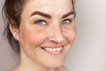 Obraz premium Smiling caucasian woman's face with freckles or age spots, melasma. Woman likes her skin. Close up Photo