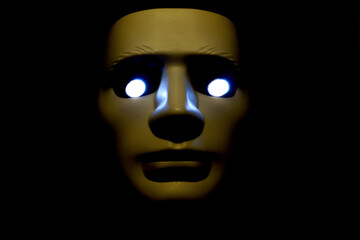 white mask with illuminated eyes on a black background