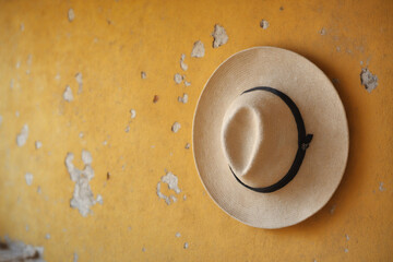 Straw hat with black band on distressed yellow wall with vintage texture