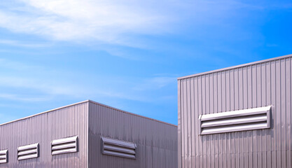 Fototapeta premium 2 factory warehouse industrial buildings with aluminium ventilation louvers on gray corrugated steel wall against blue sky background, low angle and perspective side view with copy space