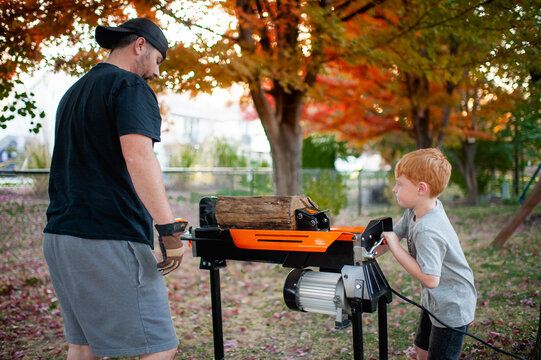 Boy 4-5 years old helps Dad split wood in the backyard in Autumn