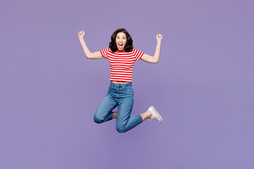Full body young woman she wear red striped t-shirt casual clothes jump high do winner gesture clench fist say yes isolated on plain pastel light purple background studio portrait. Lifestyle concept.
