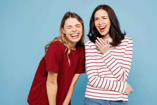Young cheerful happy funny Caucasian couple two friends women wear red casual clothes together look camera laugh isolated on pastel plain light blue cyan background studio portrait. Lifestyle concept.