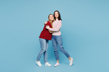 Full body young smiling happy fun couple two friends women wearing red casual clothes together hug look camera isolated on pastel plain light blue cyan background studio portrait. Lifestyle concept. © ViDi Studio
