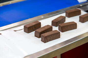 Chocolate bars moving on conveyor belt during production in factory