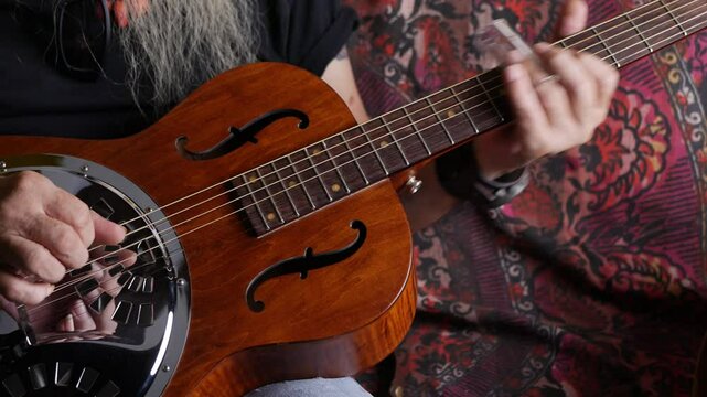 Male musician hand play Vintage Resonator acoustic dobro blues slide guitar.