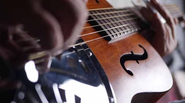 Male musician hand play Vintage Resonator acoustic dobro blues slide guitar.