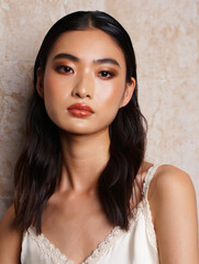 Glamorous Asian Woman with Stunning Makeup Against a Soft Beige Backdrop