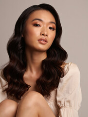 Elegant Asian Beauty with Luxurious Makeup on a Beige Background