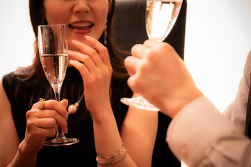 A close-up view of a man's hand tenderly covering a woman's hand on a wooden table, symbolizing romance, intimacy, or support. The setting suggests a warm, elegant environment