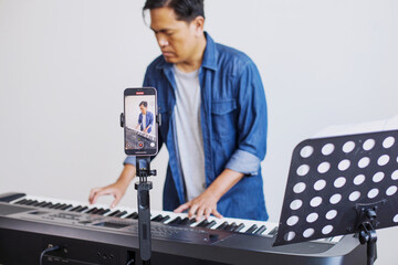 Musician Playing Piano Keyboard While Doing Online Streaming Using Smartphone
