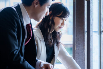 A businessman and a businesswoman in formal attire have a serious conversation while seated by the...