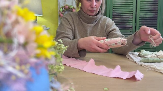 woman tears off a piece of fabric to make pants for a rabbit, master class on making an Easter bunny