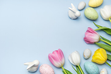 Easter eggs and tulips creating a festive border on light blue background