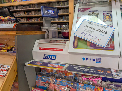France, 12 February 2025 : Store counter with lottery machine, candy display, and sign.
