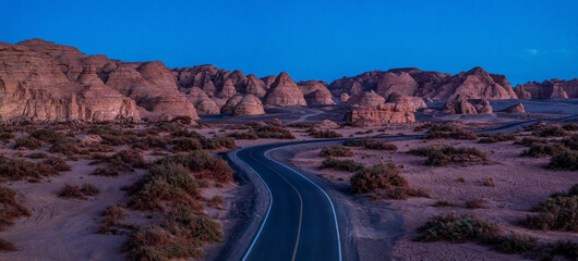 A road winding through the Yardang landform mountain at night. Famous Dahaidao no man's land natural landscape in Xinjiang, China.