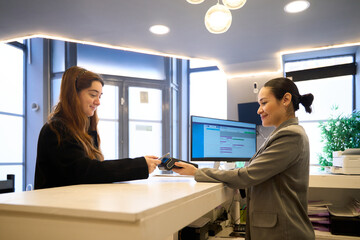 Patient paying with contactless payment at dentist reception desk