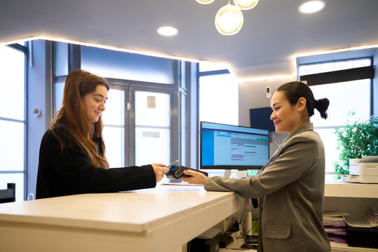 Patient paying with contactless payment at dentist reception desk