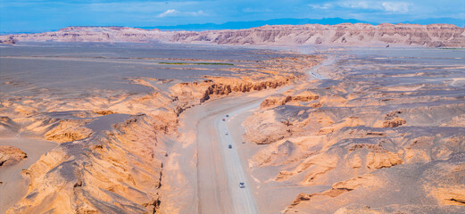 Aerial view of cars driving through a canyon in desert. Famous Dahaidao no man's land natural...