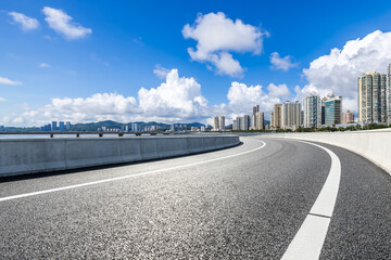 Asphalt road leading to the modern city under blue sky