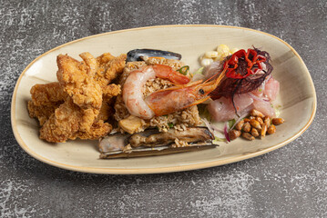 Delicious peruvian seafood platter combining fried fish, ceviche, chaufa rice and grilled razor clams