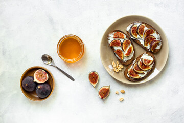 Figs and cheese toasts on the plate with jar of honey, top view