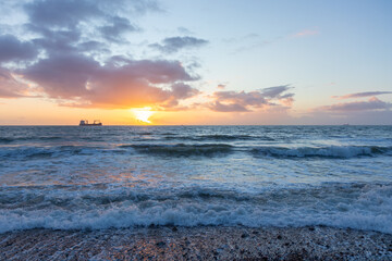 Sunset sky over the English Channel with a silhouette of a cargo ship at horizon, La-Manche, France
