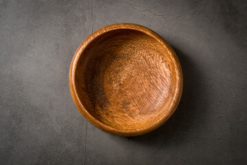 Top view of empty wooden nuts bowl on dark grey stone table