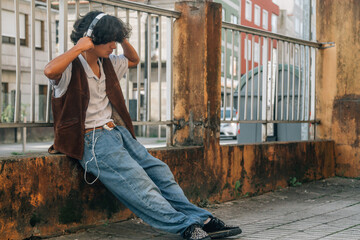 young man sitting on the street listening to music with headphones