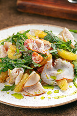 Portion of smoked turkey salad with arugula and oranges