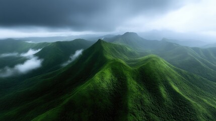 Lush green mountain range shrouded in mist.  Vast, verdant peaks rise beneath a dramatic sky, hinting at a cool, misty atmosphere