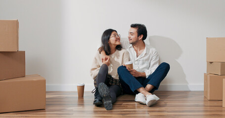 In a new flat, a gallant man and a cheerful woman sit with coffee cups. They chat about decorating ideas and household equipment.
