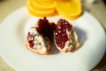 Pomegranate Seeds in Peel on White Plate with Orange Slices