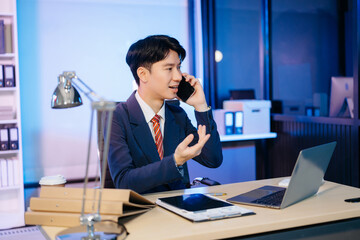 Asian Businessman analyzing reports in a modern office, working on a computer. Perfect for...