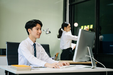 Fototapeta premium Young businessman working at office with laptop, tablet and taking notes on the paper..