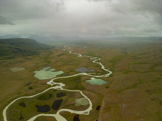 A photo from a quadcopter in one of the protected parks of Altai, where white rivers flow and there are many lakes of different colors, there are mountains nearby. Altai meanders.